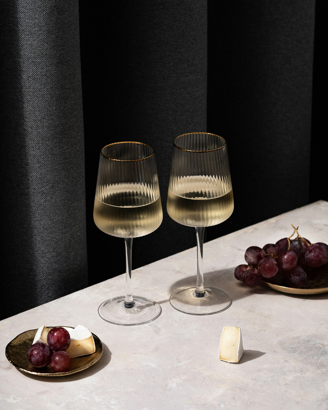 deux verres de vins blancs et leur accord parfait de raisons rouges sur une jolie table en marbre