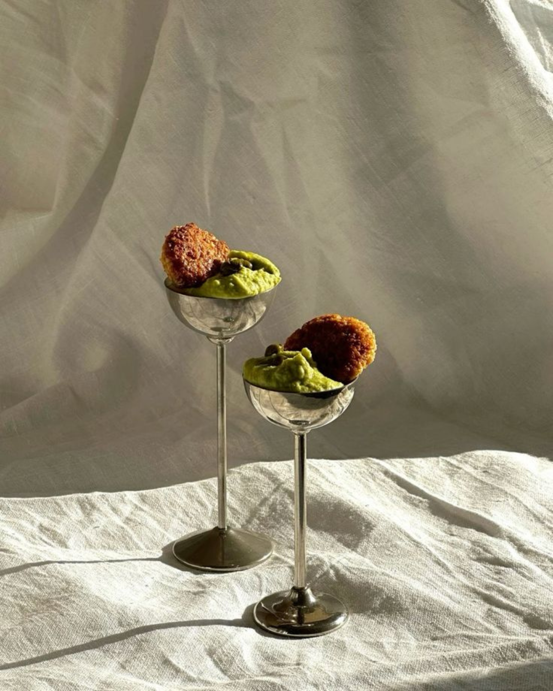 Verrines originales avec purée verte et croquettes croustillantes, servies dans des coupes à pied sur une nappe en lin