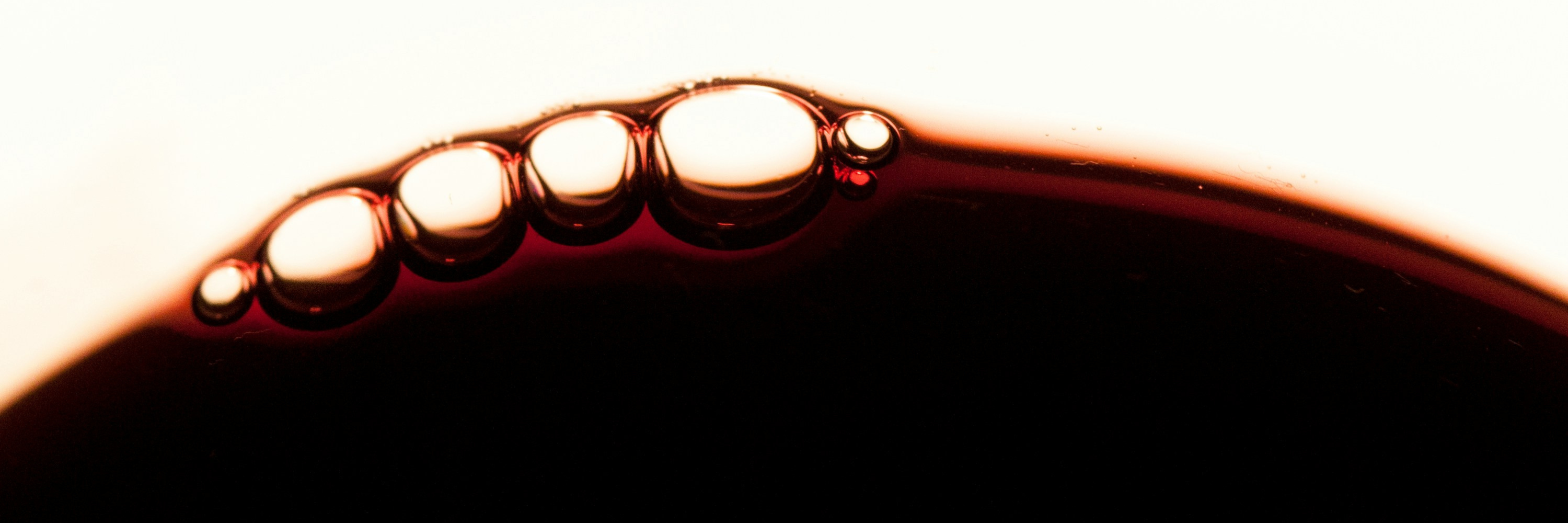 Gouttes et bulles formées à la surface d’un vin rouge, mettant en valeur sa texture et sa richesse aromatique