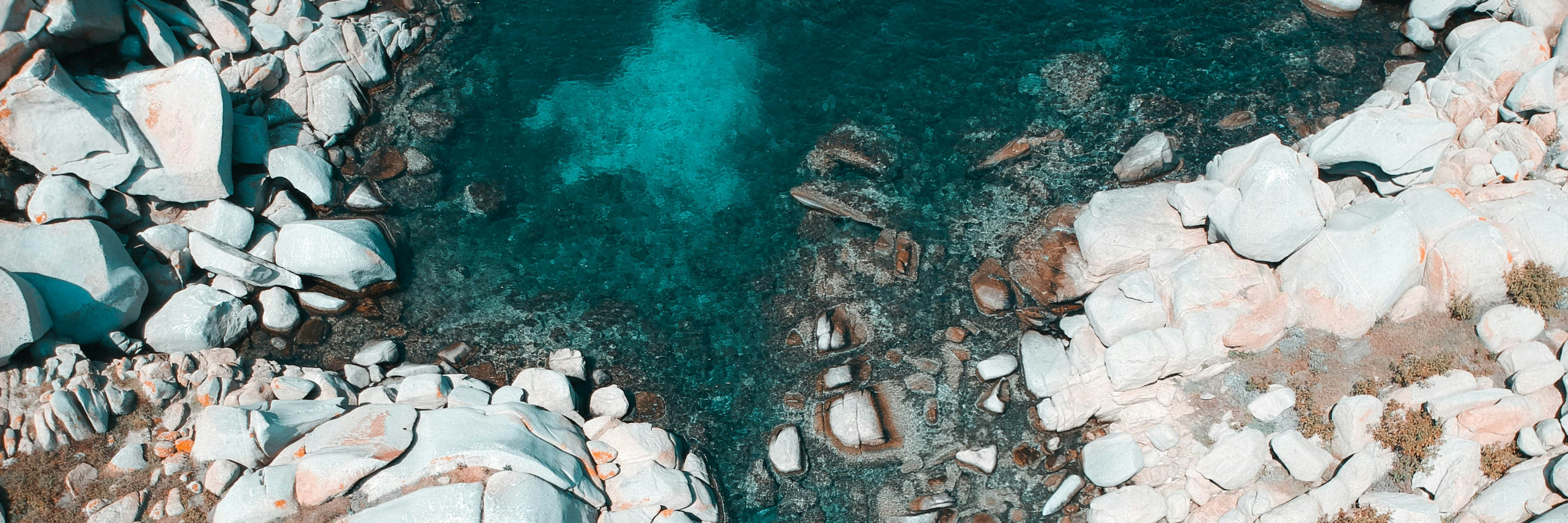 Vue aérienne des eaux turquoise et des rochers de Corse, illustrant la beauté sauvage de l’île méditerranéenne