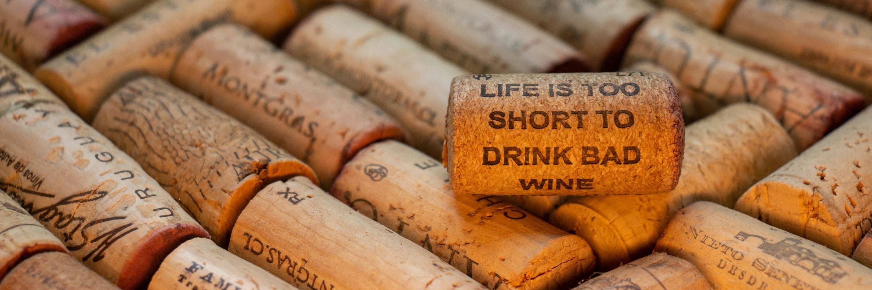  Collection de bouchons de vin avec une citation gravée "Life is too short to drink bad wine", rappelant l’importance de choisir un bon vin