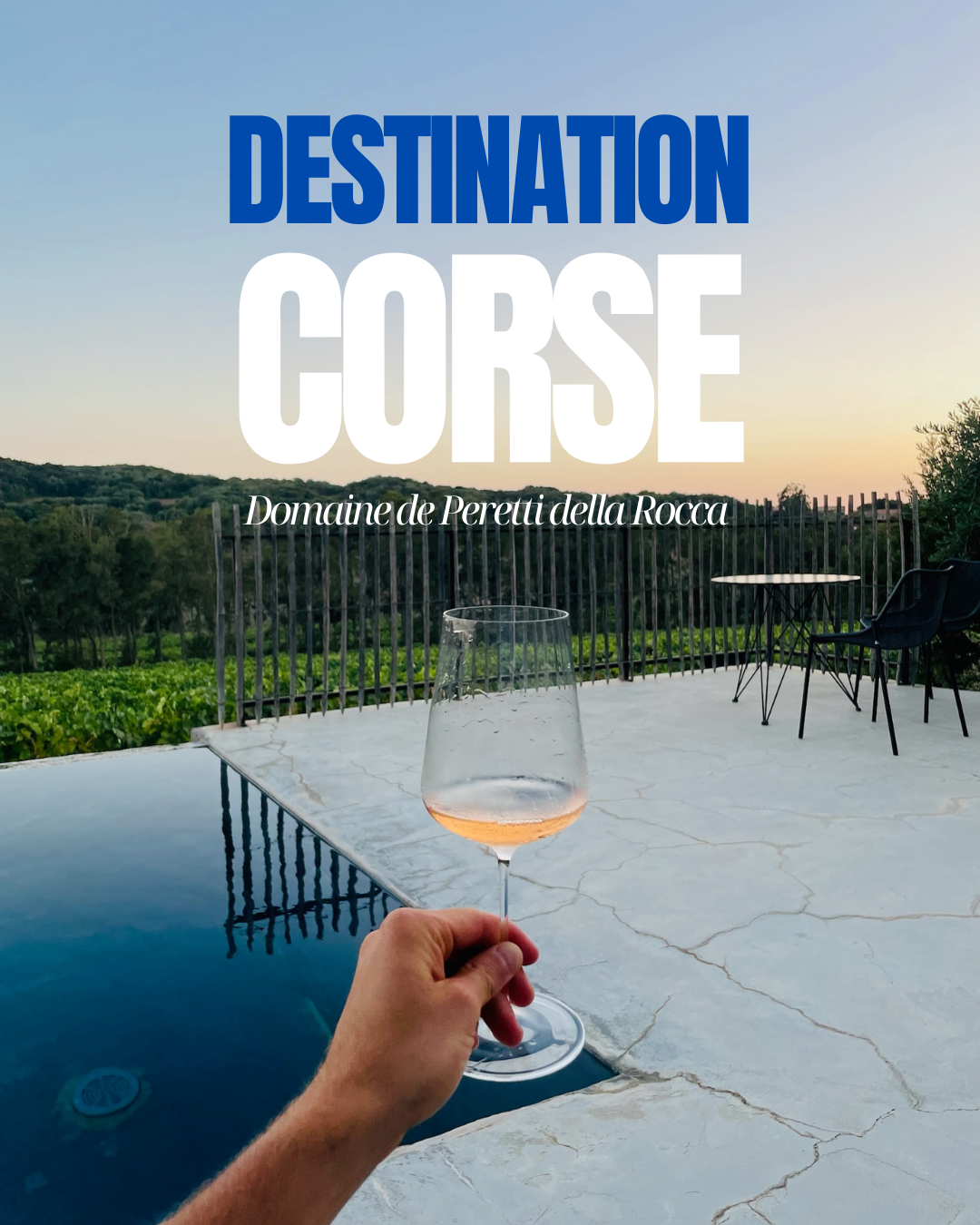 Un verre de vin rosé tenu devant une piscine avec vue sur les vignes du Domaine de Peretti della Rocca en Corse au coucher du soleil. Ambiance estivale et détente avec un vin d’exception